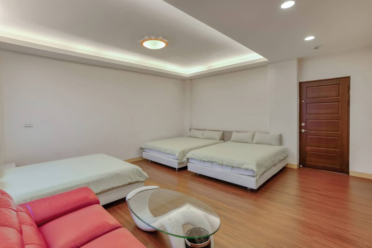 A modern hotel room with two single beds, a glass coffee table, and a wooden floor.