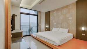 Une chambre d’hôtel moderne dotée d’un grand lit, d’un bureau et offrant une vue sur la ville grâce à de grandes fenêtres.