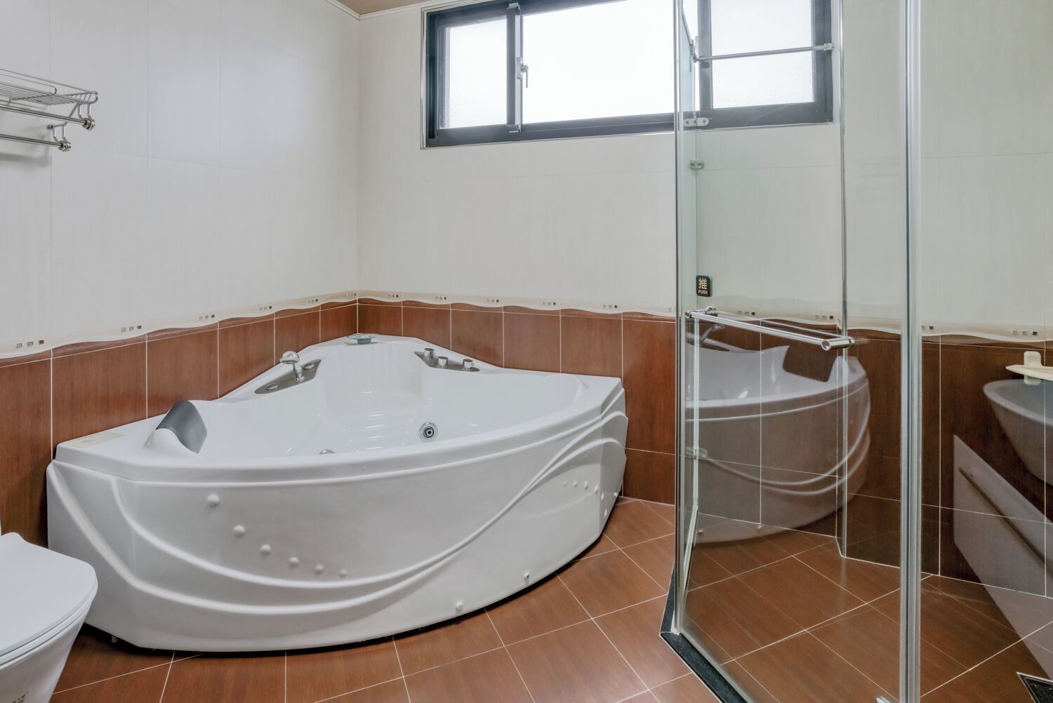 A modern bathroom with a large freestanding bathtub, a glass-enclosed shower, and a window providing natural light.