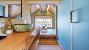 Une salle de bain de style japonais traditionnel, avec un meuble-lavabo en bois, un lavabo en céramique verte et une fenêtre donnant sur un paysage verdoyant.