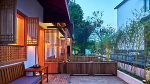 Une terrasse en bois avec un banc et une table, entourée de clôtures en bois et de plantes.