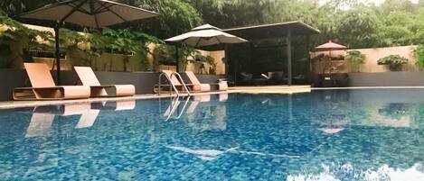 Una piscina al aire libre, sillones reclinables de piscina