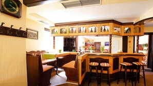 A bar area with wooden stools, a bar counter, and a clock on the wall. - Hotel Meyer (Hildesheim)