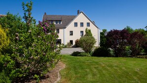 A two-story house with a sloped roof, a front entrance, and a well-maintained lawn. - Hotel Meyer (Hildesheim)