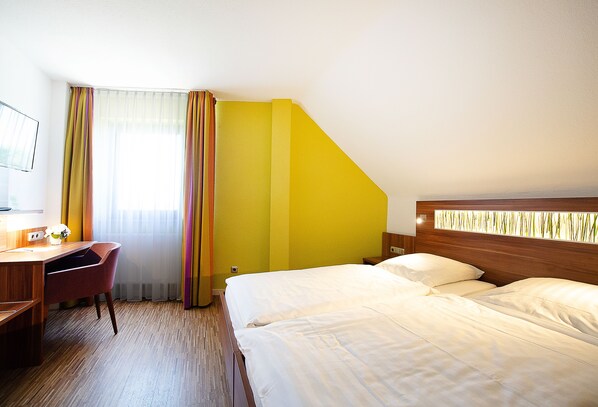 A hotel room with a desk, two beds, a chair, and a window with curtains. - Hotel Meyer (Hildesheim)
