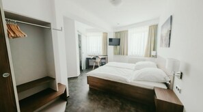 A hotel room with a wooden bed, a desk, and a TV. - Hotel Meyer (Hildesheim)