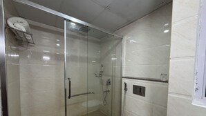 A modern bathroom with a glass-enclosed shower, a white toilet, and a marble-tiled floor.
