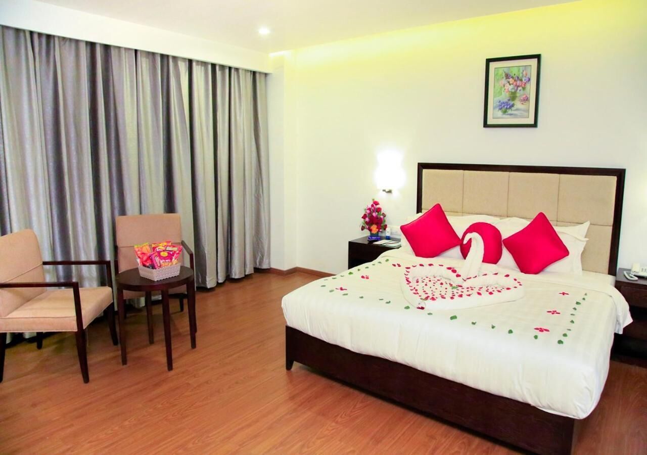 A hotel room with a bed, a chair, a nightstand, and a lamp.