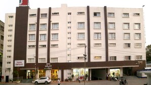 A multi-story hotel with a central entrance, a parking area, and a visible sign for 'Clarks Inn'.