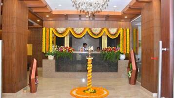 A reception area with a chandelier, floral decorations, and a reception desk.