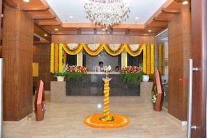 A reception area with a chandelier, floral decorations, and a reception desk.