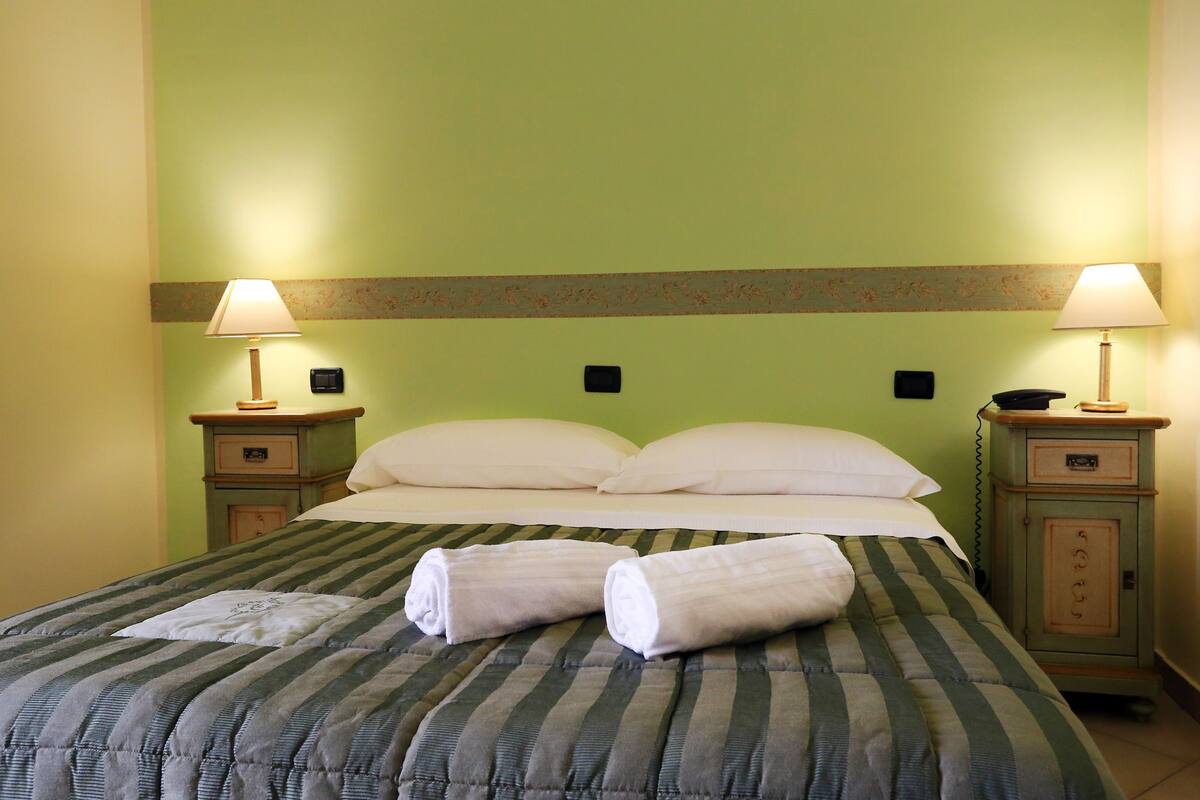 Ein Hotelzimmer mit einem Bett, zwei Nachttischen, Lampen und einem Beistelltisch.