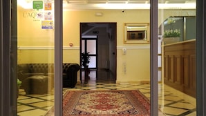 A hotel lobby with a checkered floor, a patterned rug, a sofa, and a door leading to another room.
