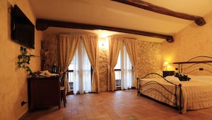 A bedroom with a bed, a desk, a television, and a stone wall.