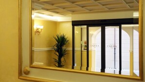 A hotel entrance with a mirrored wall reflecting the interior.