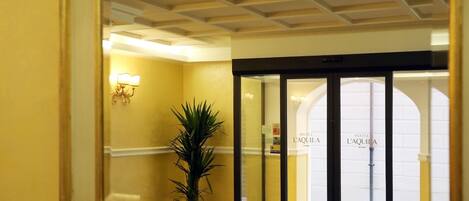 Entrada de hotel con un muro espejado que refleja el interior.