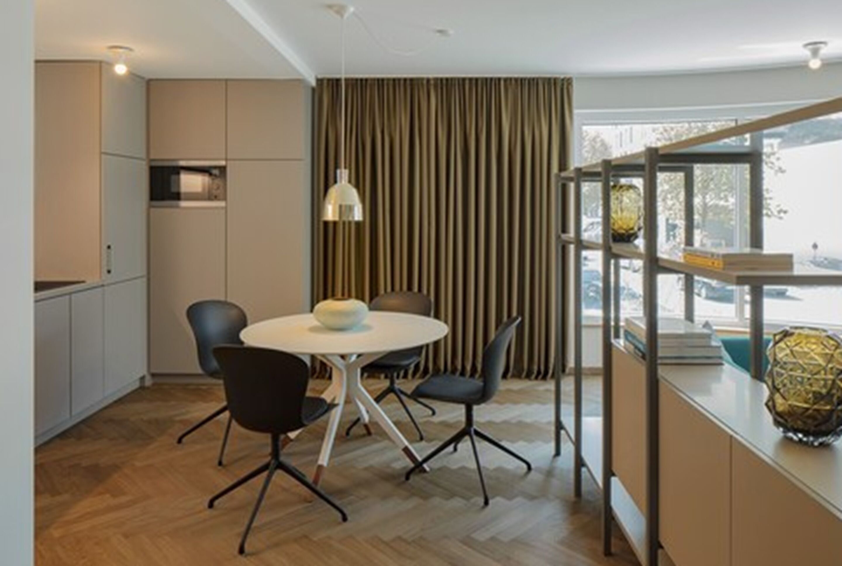 Una cocina moderna con comedor, suelo de madera y vistas al exterior.