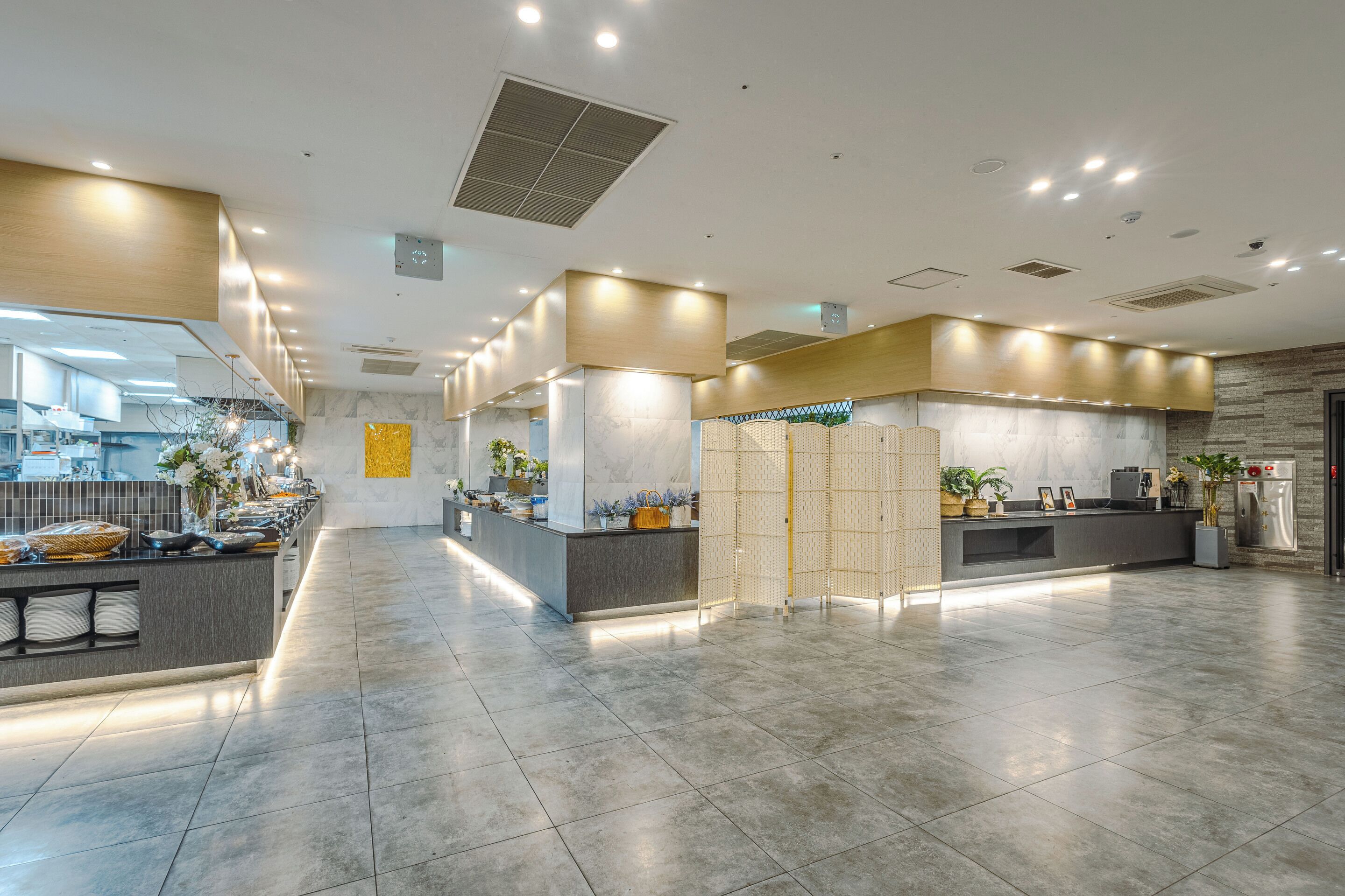 A spacious lobby with a reception desk, seating area, and a kitchen in the background.