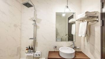 Un baño moderno con una bañera independiente, un lavabo integrado con tocador de madera, un perchero de pared y un espejo grande.
