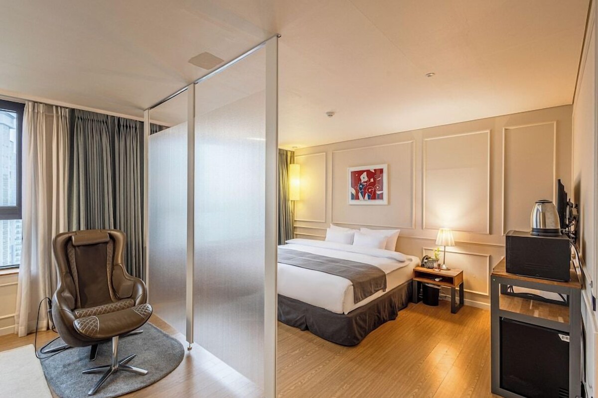 Una habitación de hotel con cama, una silla, un escritorio y una máquina de café.