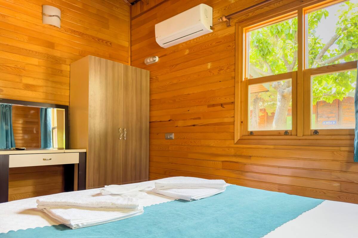 A wooden-paneled room with a bed, a desk, and a wardrobe.
