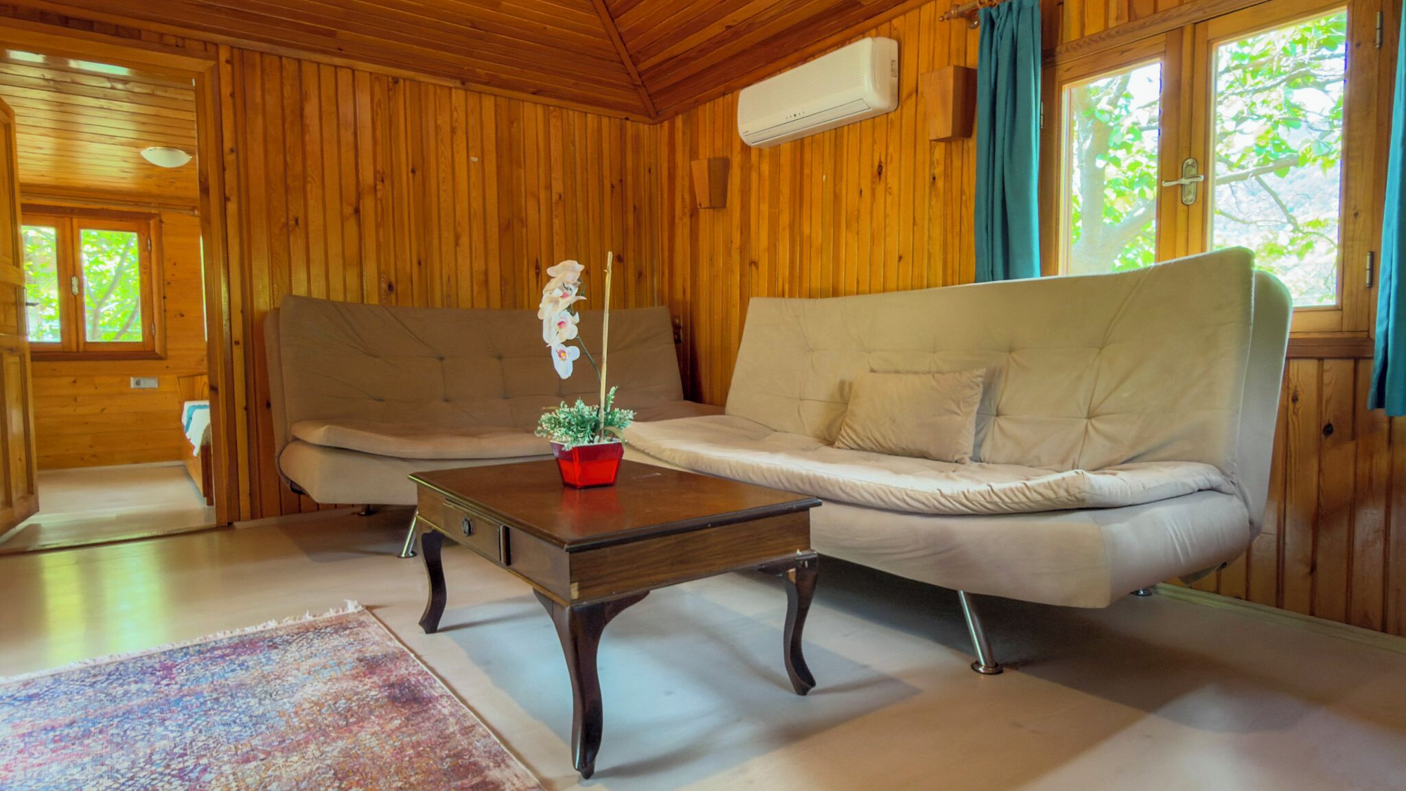 Un interior de madera con un sofá, una mesa de centro y una planta en maceta.