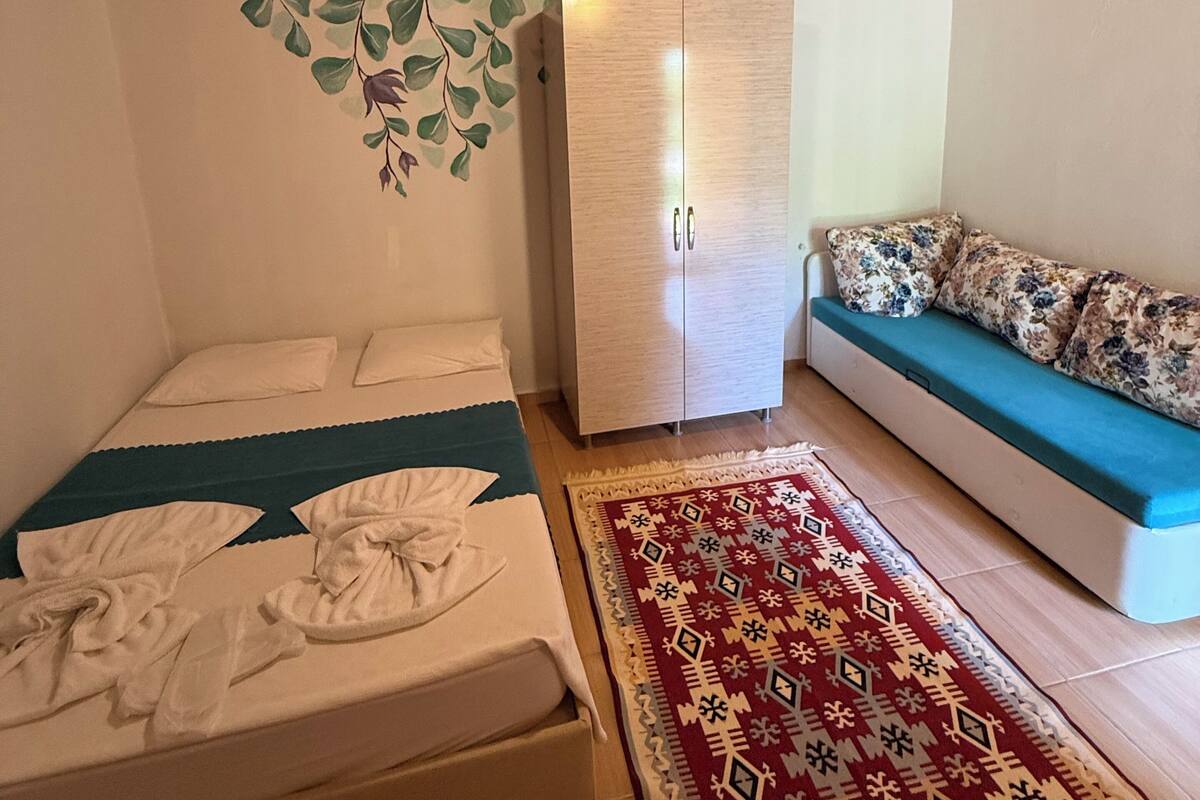 A room with a bed, a wardrobe, a sofa, and a patterned rug.