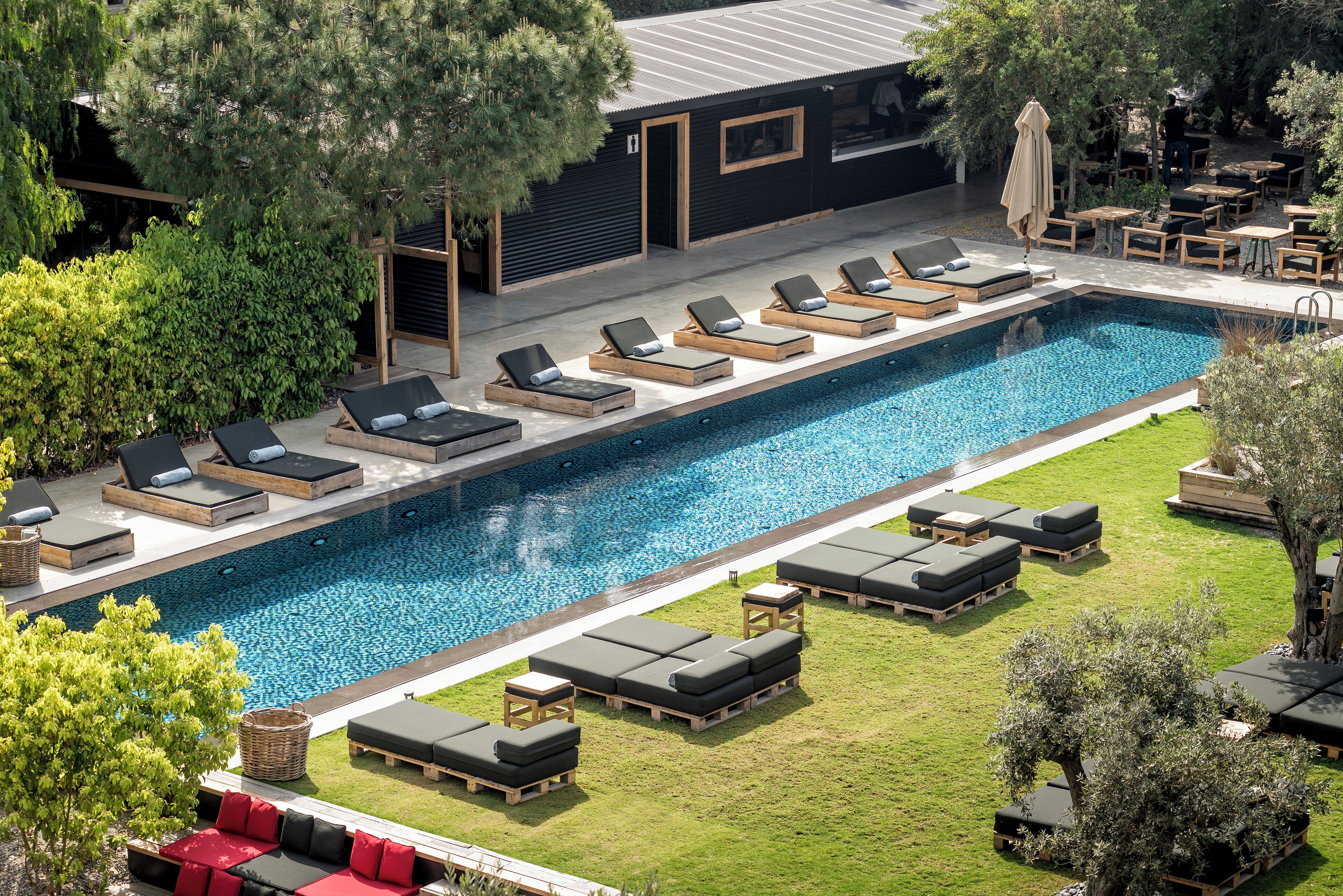 A swimming pool with sun loungers and a small building in the background.