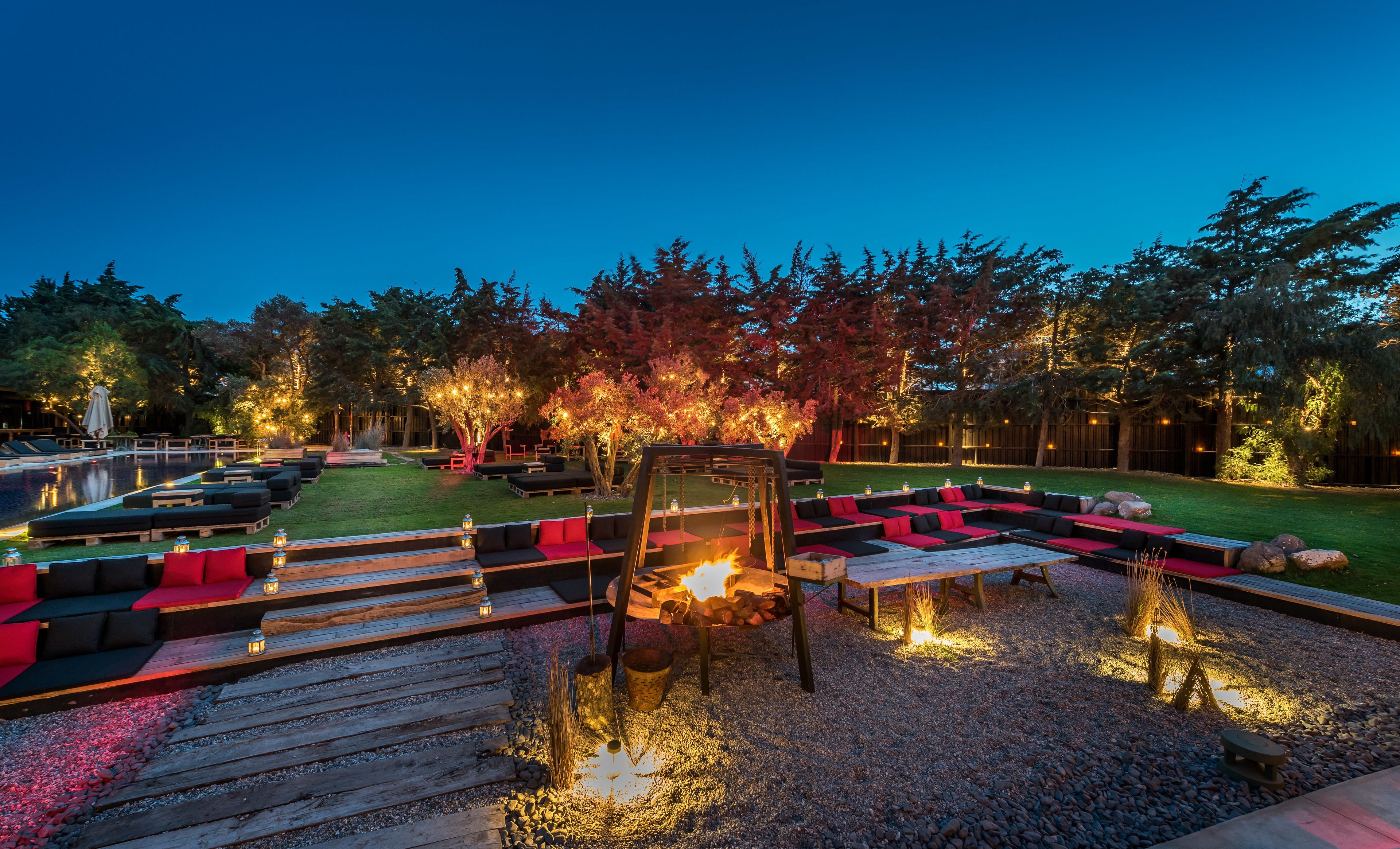 Un área de estar al aire libre con una chimenea, sillones reclinables y una piscina.