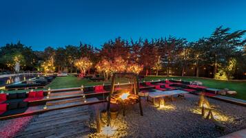 Un área de estar al aire libre con una chimenea, sillones reclinables y una piscina.