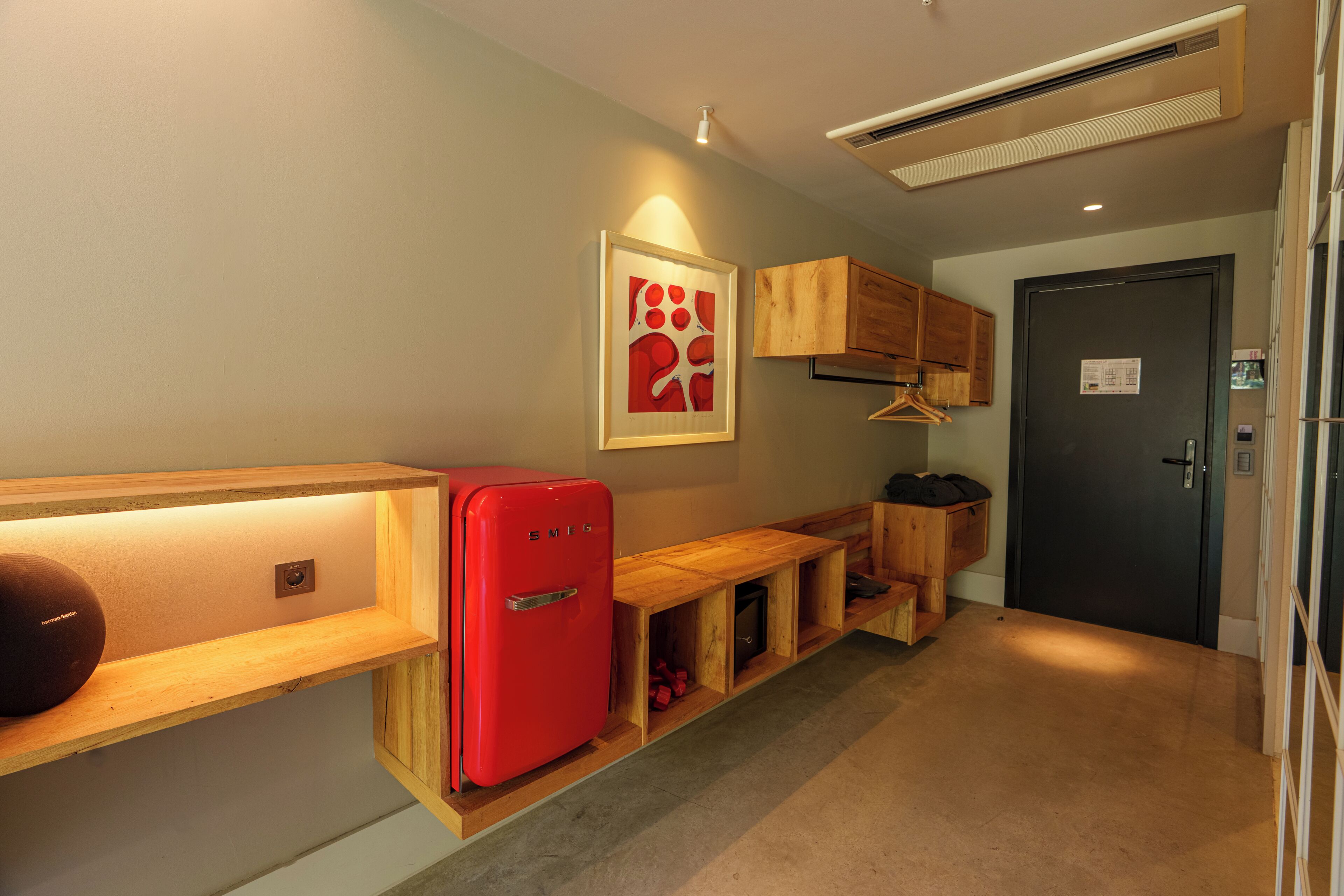 A compact kitchen with a red refrigerator, wooden cabinets, and a framed artwork on the wall.