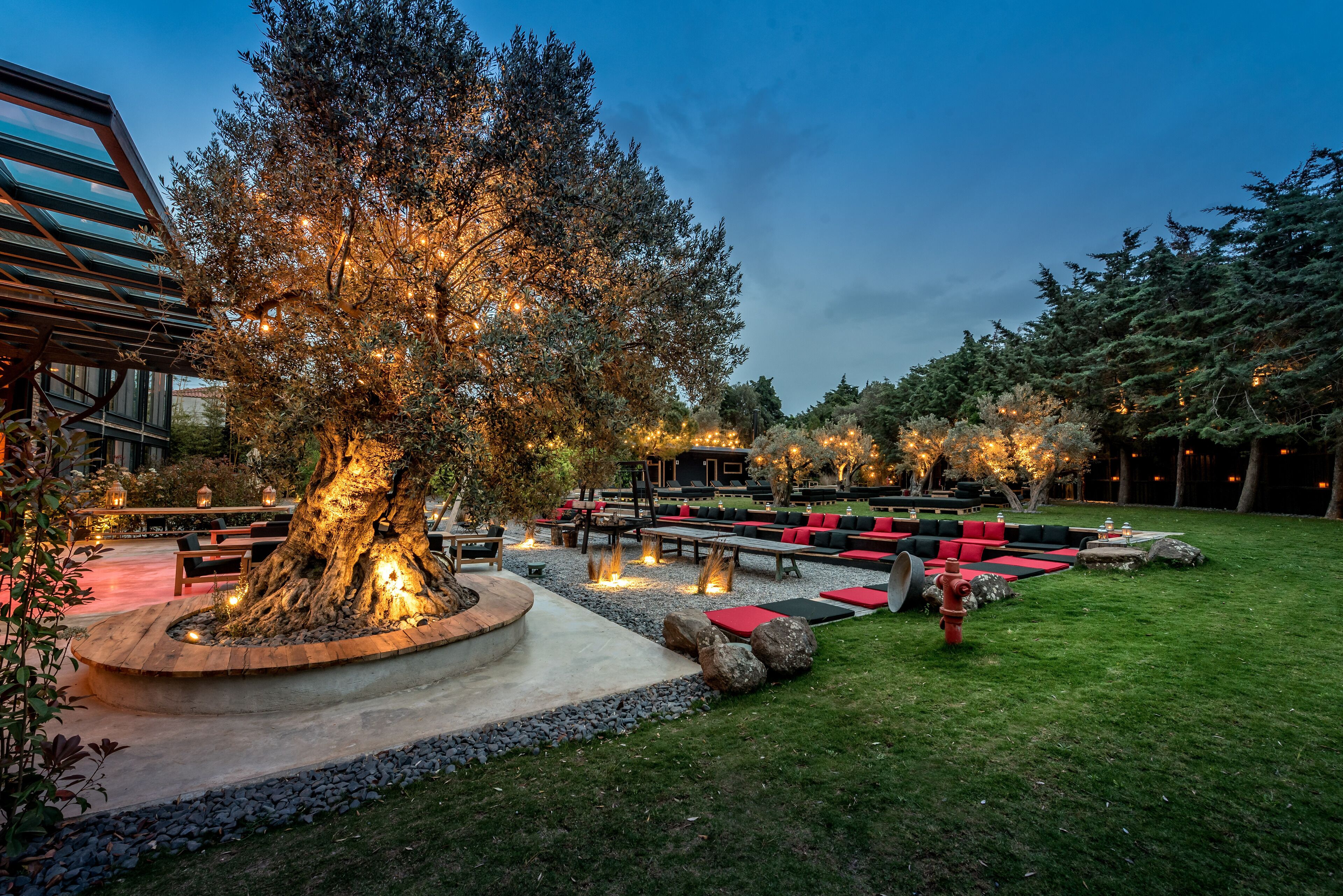 An outdoor seating area with round tables, benches, and a fire pit.