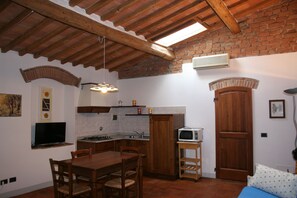 A compact kitchen with wooden cabinets, a built-in microwave, and a dining area with a table and chairs.