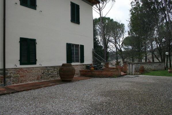 A building with a white facade, green shutters, and a gravel driveway.