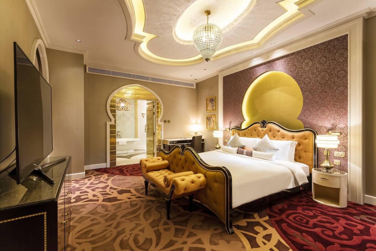 A hotel room with a large bed, a sofa, a TV, and a desk.