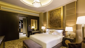 A spacious hotel room with a large bed, a sitting area with a bench, a desk, and a mirror. - Ezdan Palace Hotel (Doha)