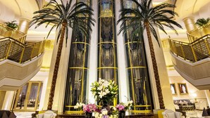 A grand lobby with a large glass dome ceiling, two palm trees, and a central floral arrangement. - Ezdan Palace Hotel (Doha)