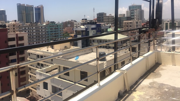 Un immeuble de grande hauteur doté de nombreux balcons et offrant une vue sur d’autres bâtiments en arrière-plan.