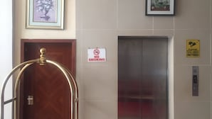 Un ascenseur, un panneau «interdiction de fumer» et un chariot avec un coussin rouge.