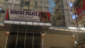 Un hôtel avec une enseigne indiquant « Rungwe Palace Hotel » et un numéro de téléphone.