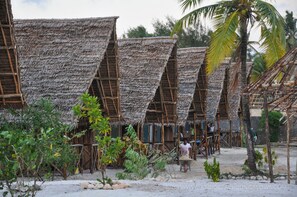 Traditional huts with steeply pitched roofs and wooden beams offer a natural, eco-friendly retreat amidst lush vegetation.