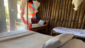 A room with two beds, one with a canopy and one without. There is a wooden chair and a small table. - New Jambo Bungalows - Hostel (Paje)