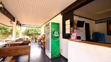 Un café con mobiliario de madera, un refrigerador marca Chang y una barra con un refrigerador azul.