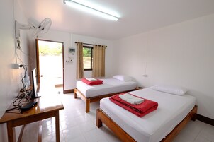 Una habitación de hotel con dos camas de madera, un escritorio con computadora, un ventilador de pared y una ventana con cortinas.