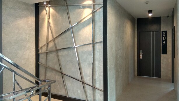 Un interior moderno con un diseño geométrico en la pared, una escalera y una puerta marcada con el número 201.