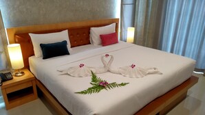 Una cama bien hecha con edredón blanco, dos almohadas y un arreglo decorativo de toallas con forma de cisne en el cubrecolchón.