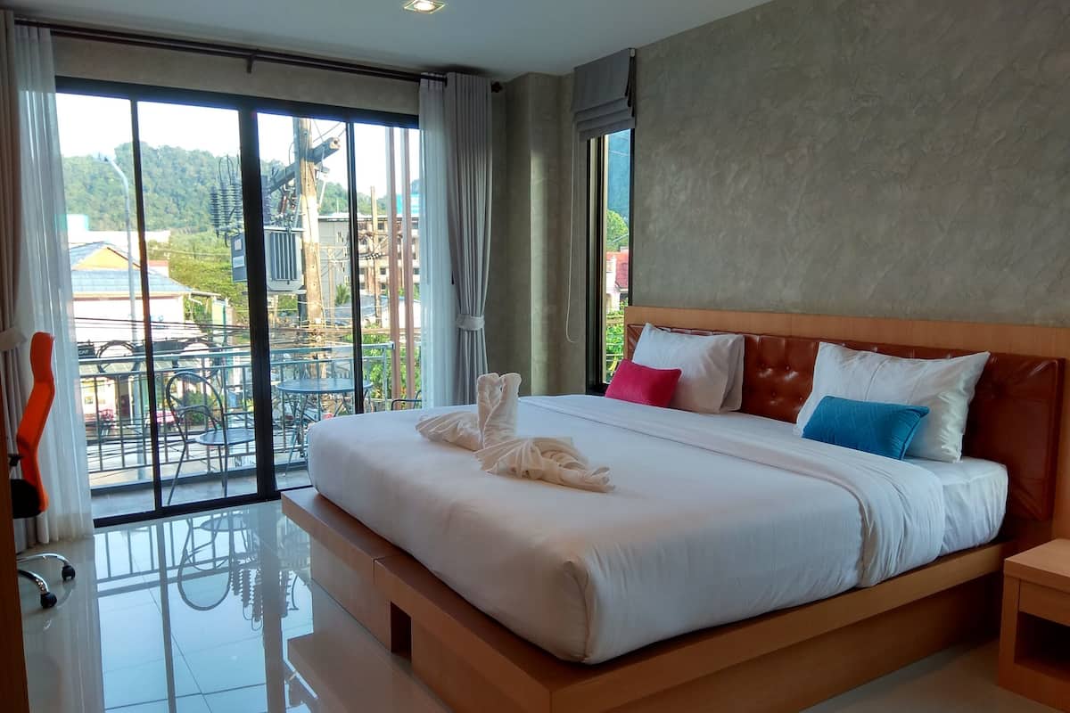 A modern hotel room with a large bed, a balcony with a view of the city, and a clean, minimalist design.