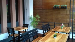 Un interior de restaurante moderno con mesas de madera, sillas negras, plantas en macetas y lámparas colgantes.