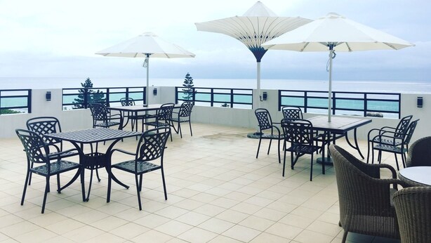 A terrace with outdoor seating and umbrellas overlooking the sea. - Hola sea view B&B (Shoufeng)