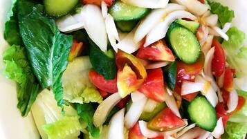 A bowl of salad with lettuce, cucumbers, tomatoes, and onions.